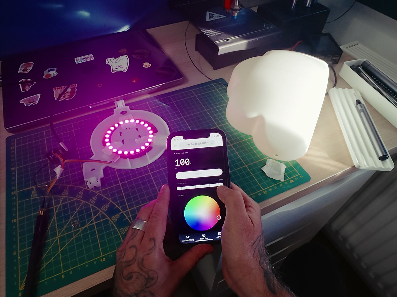 The LED ring lit magenta on the bench next to the cloud diffuser, with the lamp's own control page open on a phone